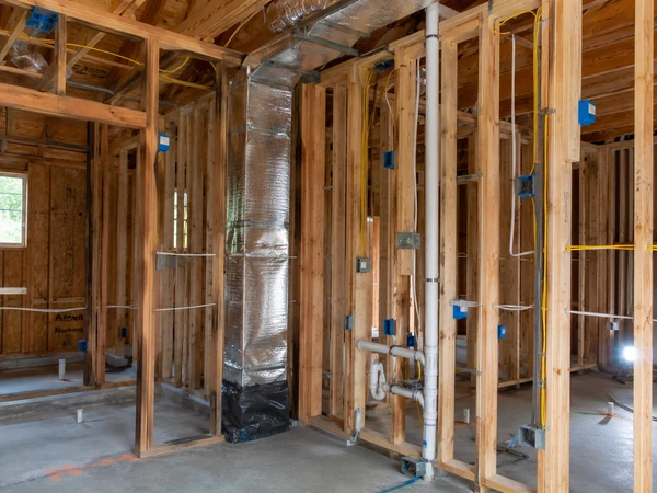 Electrical panel and rough plumbing lines installed during a garage conversion build-out